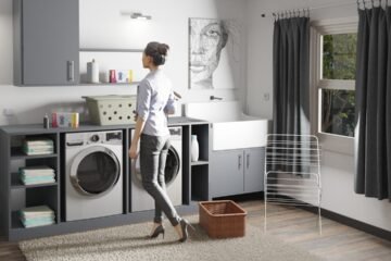 Woman standing in a laundry room next to a washer and dryer
